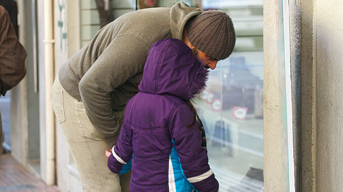 Un padre y su hija observan una vidriera céntrica de Paysandú dú durante una ola de frío.